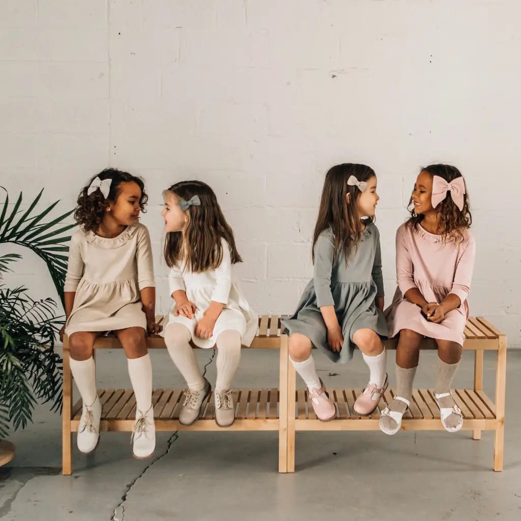 models wearing leather shoes and bows featured in colors fog, sand, peony, and terrazzo