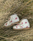 Pair of white shoes with an apple pattern on a grassy background
