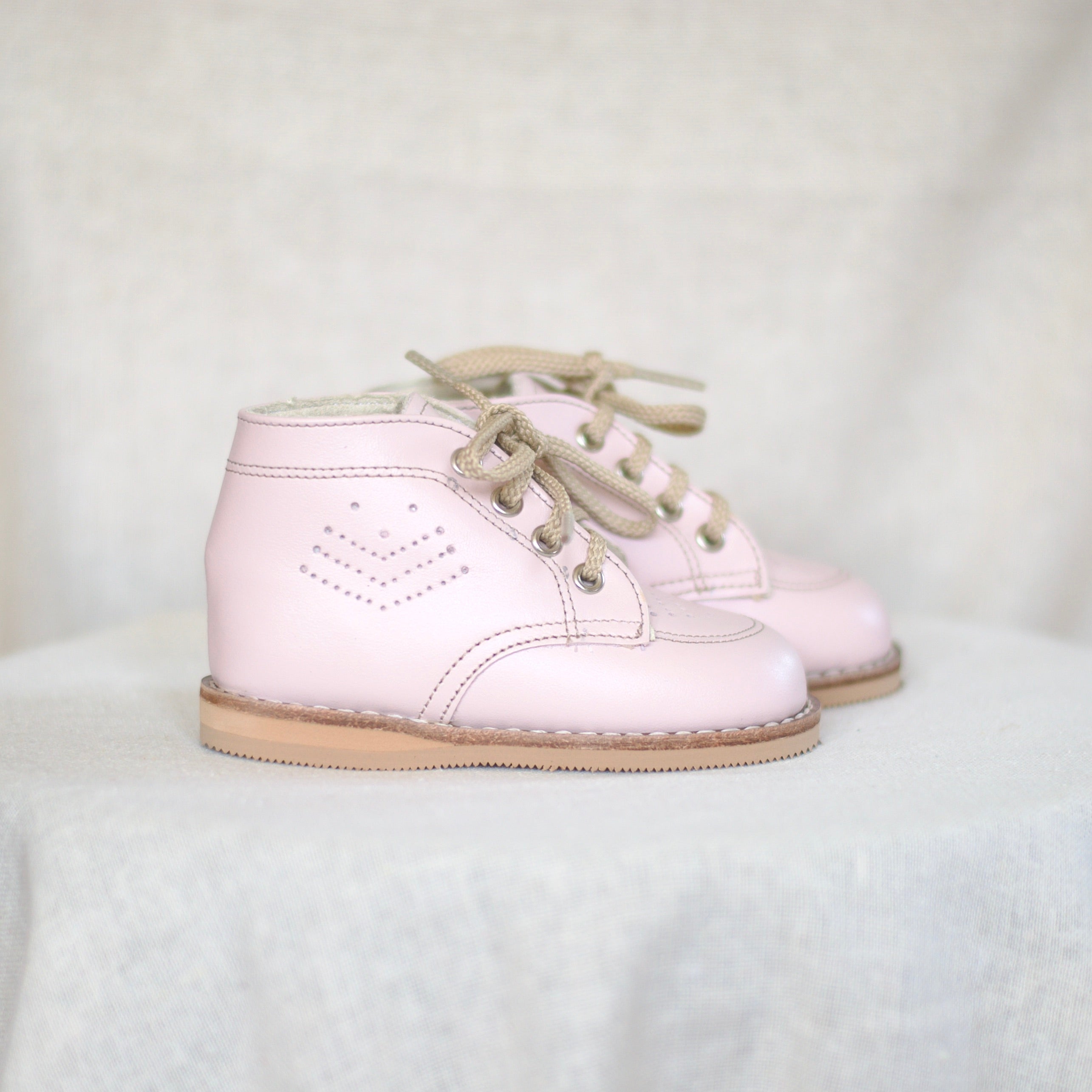Pair of pink shoes on a white fabric background