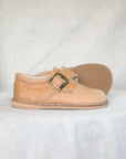 tan shoe with a buckle on a white background