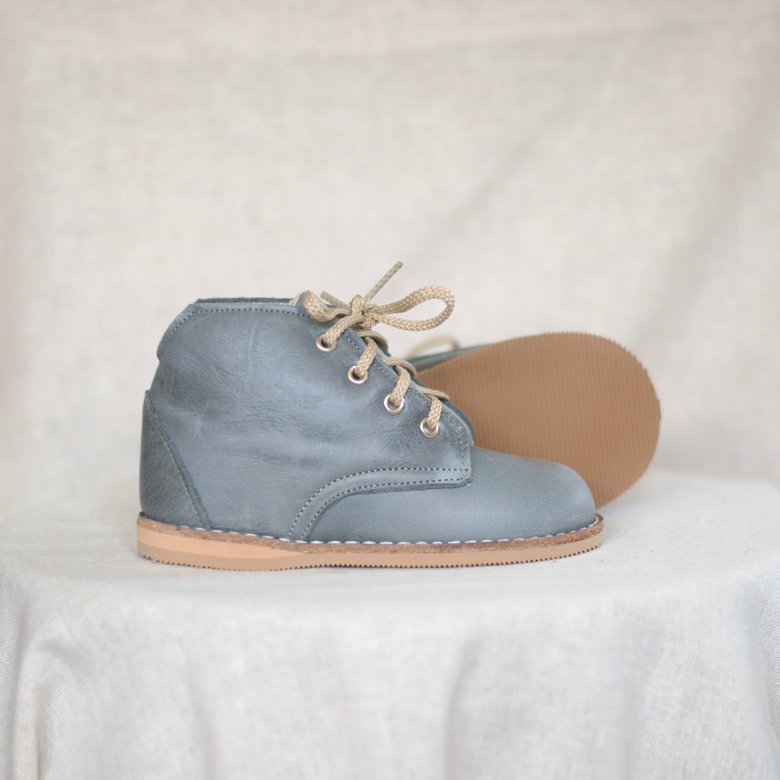 Blue suede shoe with beige laces and sole on a white background