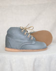 Blue suede shoe with beige laces and sole on a white background