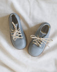 Pair of light blue shoes with beige laces on a white fabric background