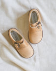 Pair of tan children's shoes on a white fabric background