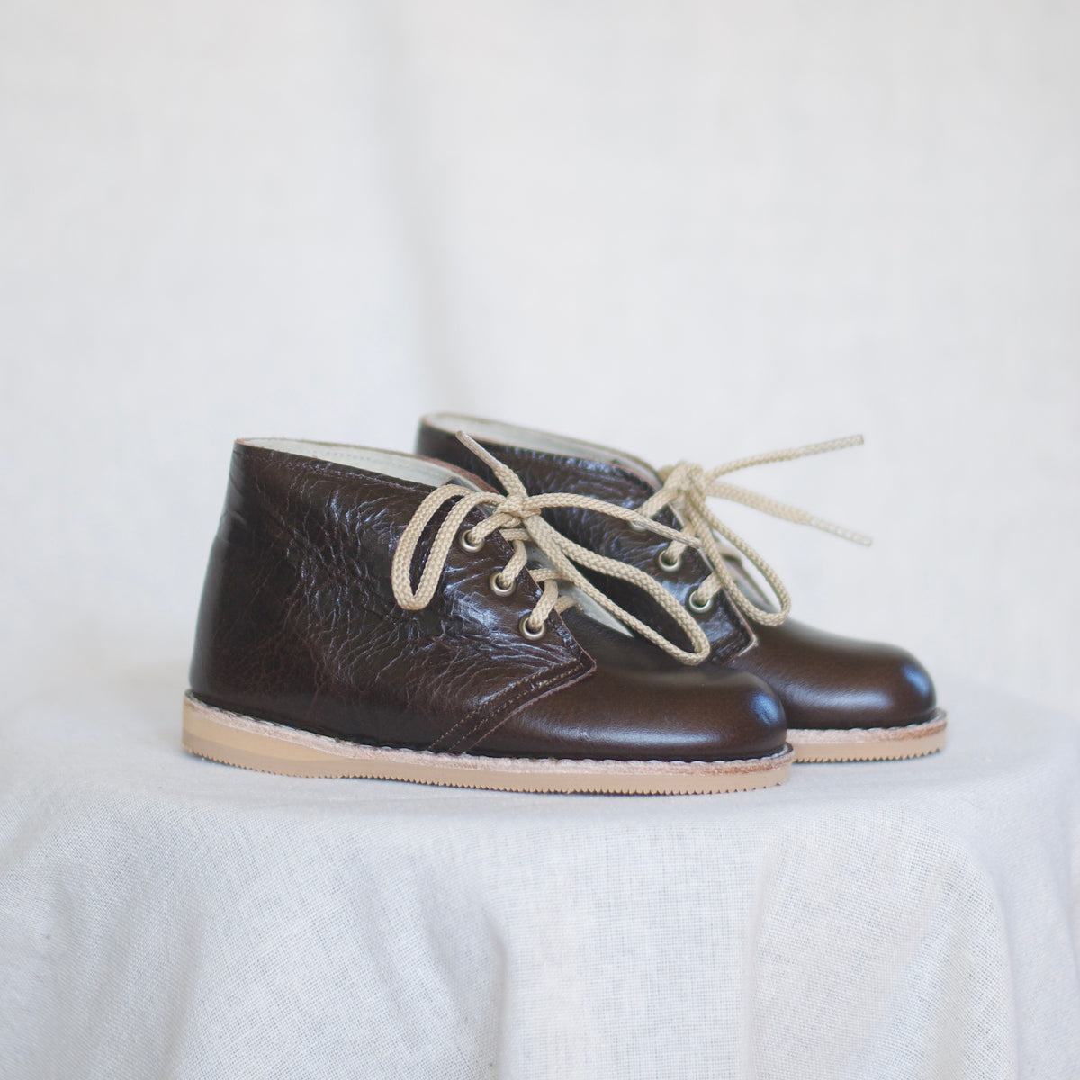 Pair of brown leather shoes with beige laces on a light background