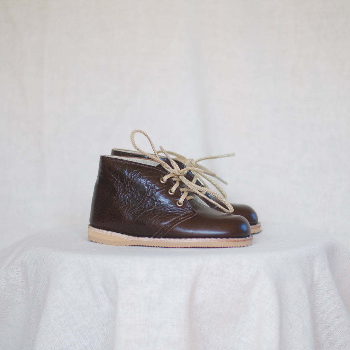Pair of brown leather shoes with beige laces on a light background