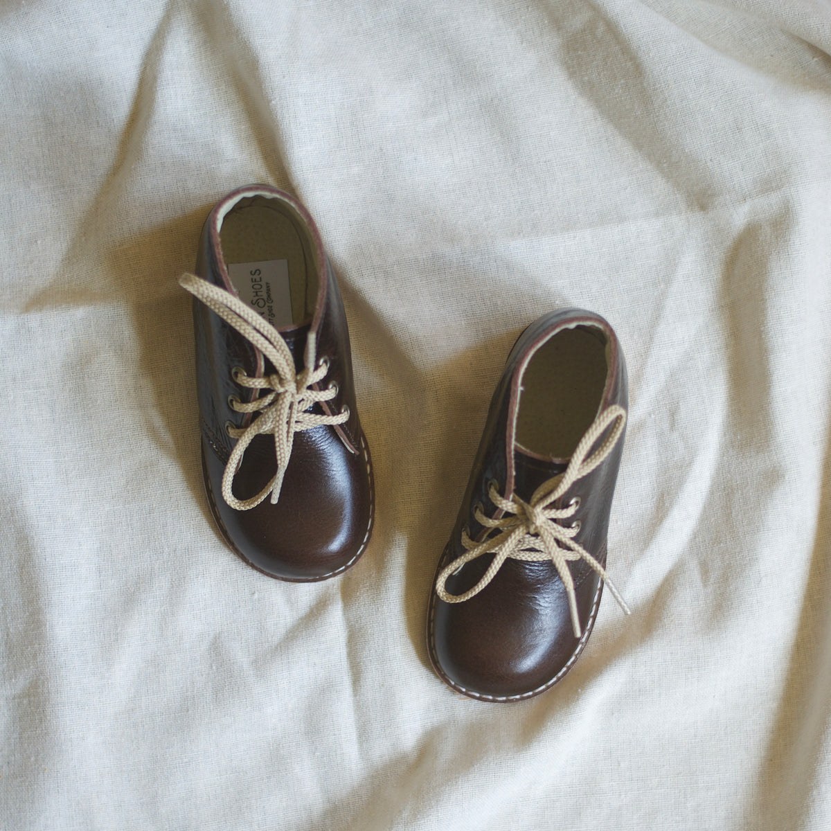 Pair of brown leather shoes with beige laces on a light background