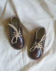 Pair of brown leather shoes with beige laces on a light background