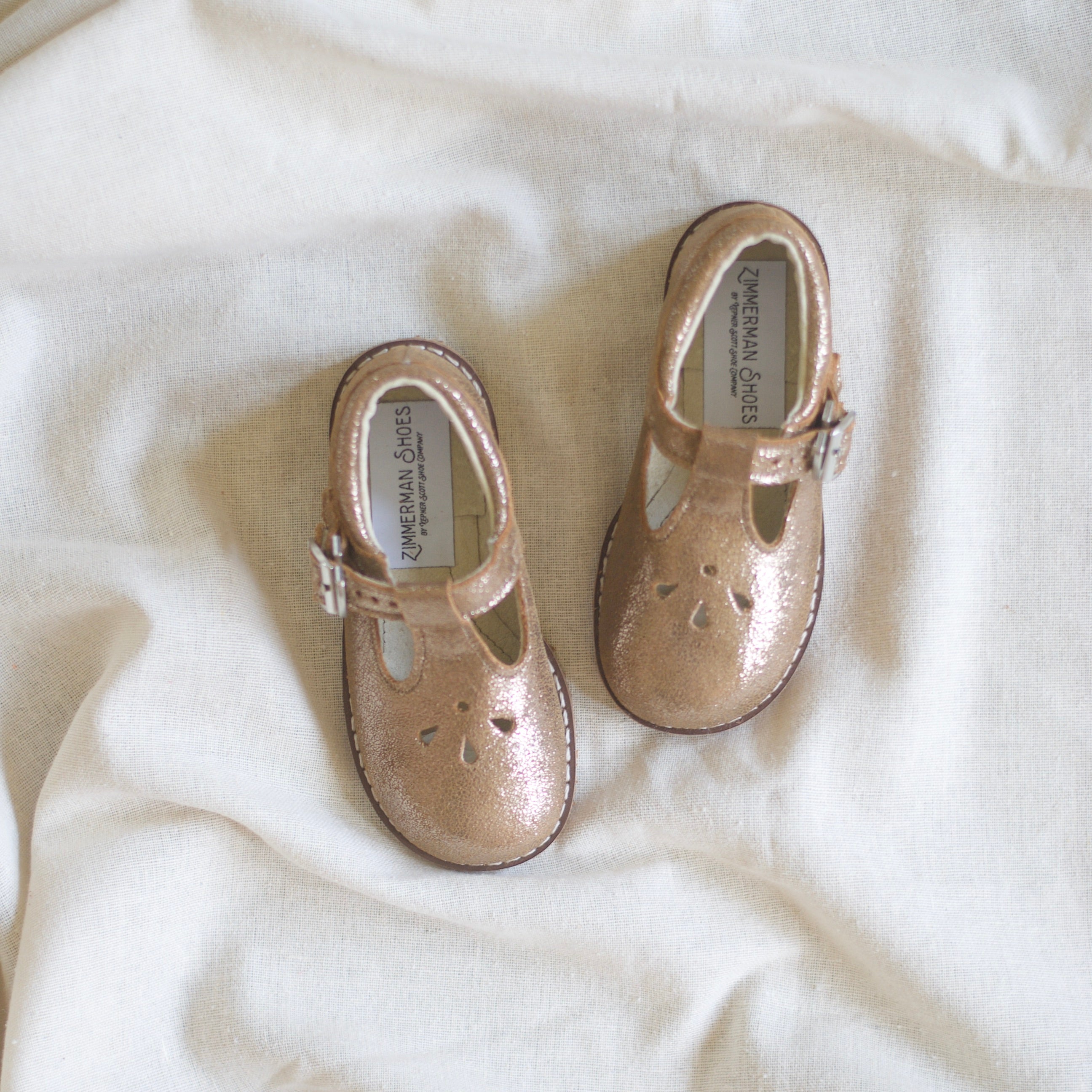 Pair of gold shoes on a white fabric background