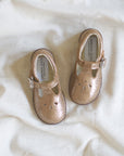 Pair of gold shoes on a white fabric background
