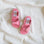 Pair of pink sandals with buckles on a white fabric background