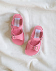 Pair of pink sandals with buckles on a white fabric background