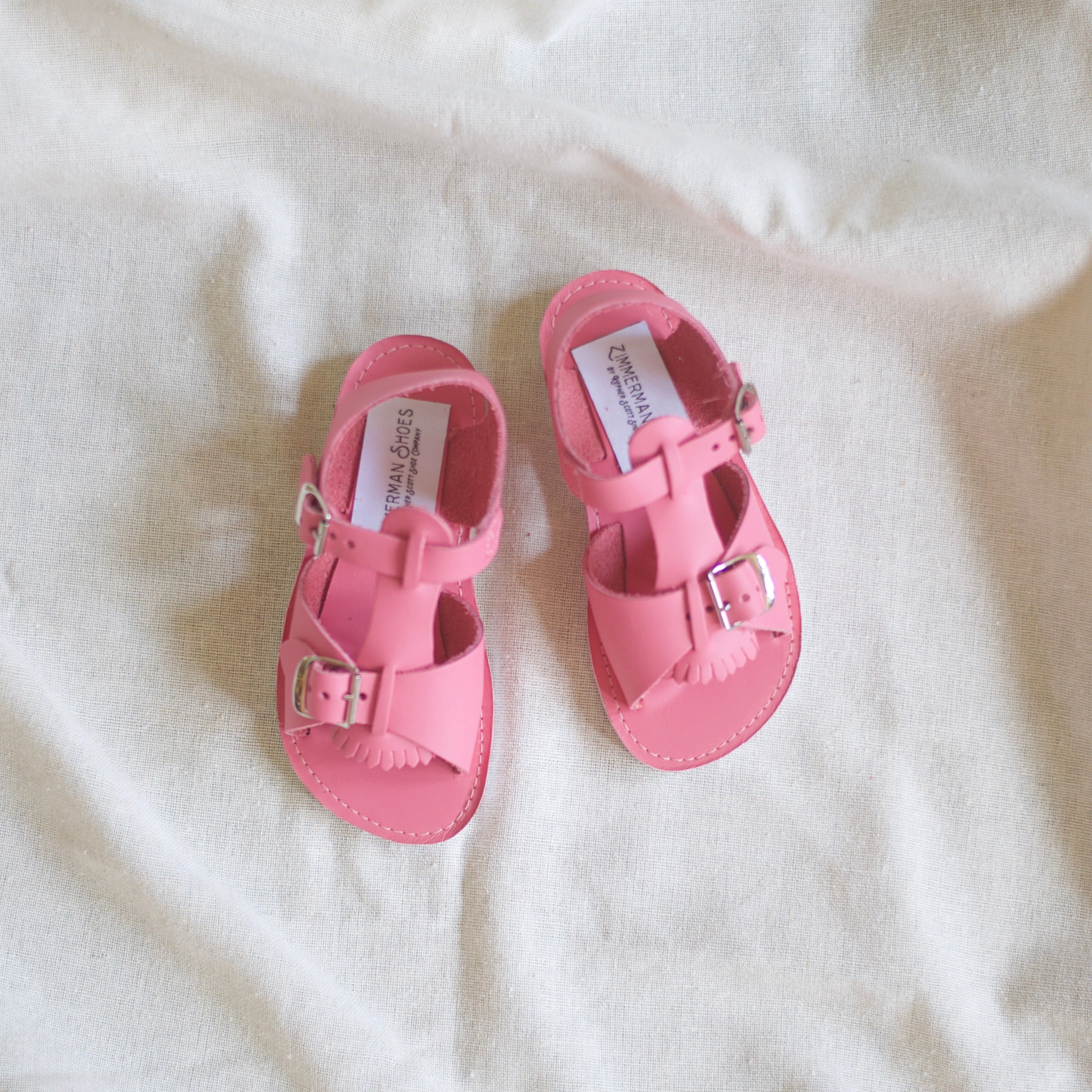Pair of pink sandals on a white fabric background