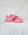 Pink sandals with buckles on a white fabric background