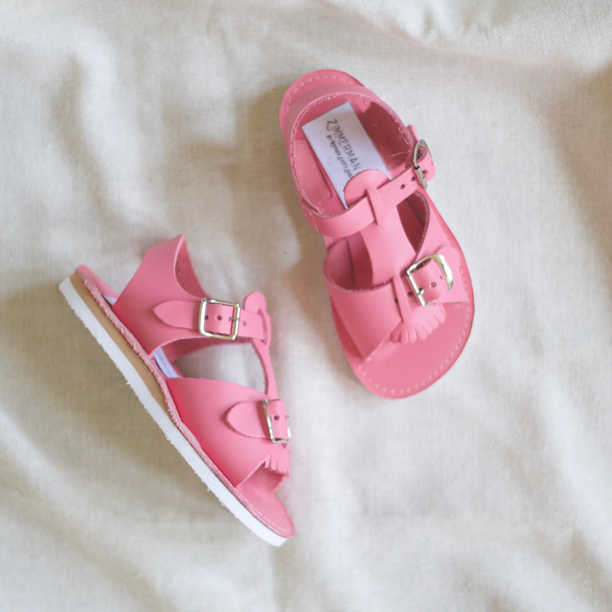 Pair of pink sandals on a white fabric background